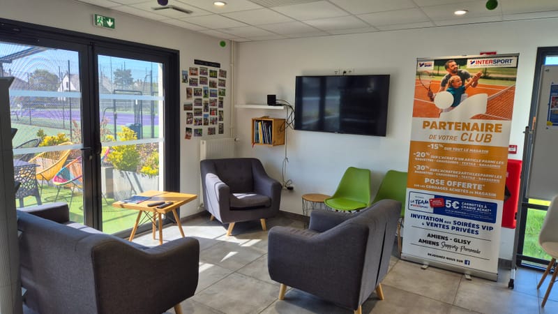 Coin salon du club-house avec vue sur les courts