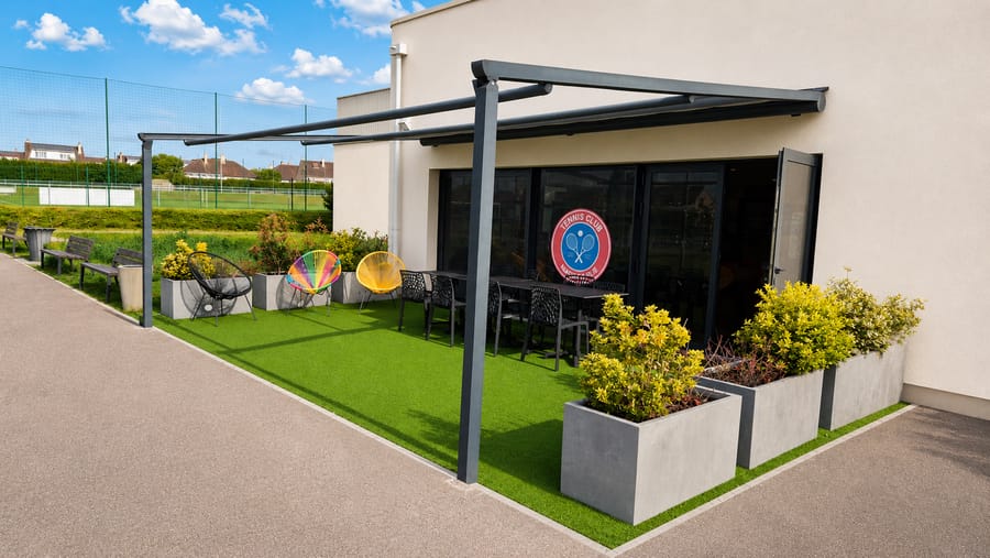 Terrasse extérieure du TCM Rivery avec pergola et fauteuils colorés